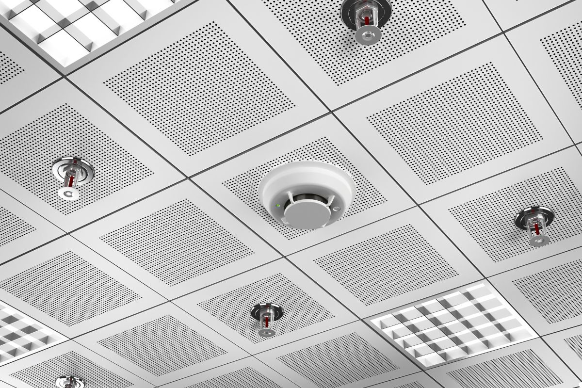 Fire alarm system mounted on the ceiling, featuring a red casing and a visible alarm indicator light.