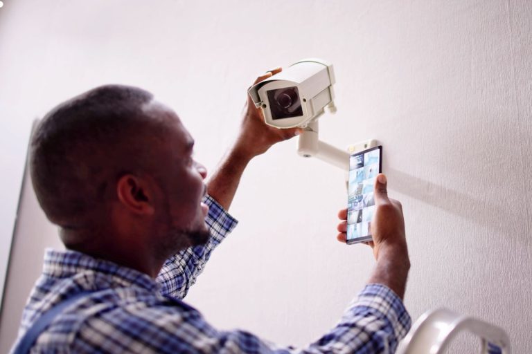 A man uses his cell phone to take a picture, directing it towards a camera with intent.