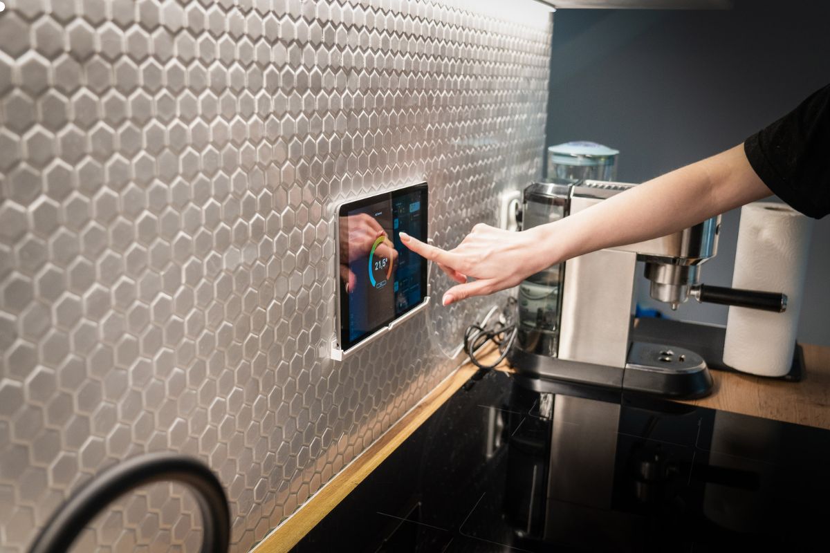 An individual utilizes an iPad to manage a kitchen device, highlighting the integration of technology in culinary tasks. 